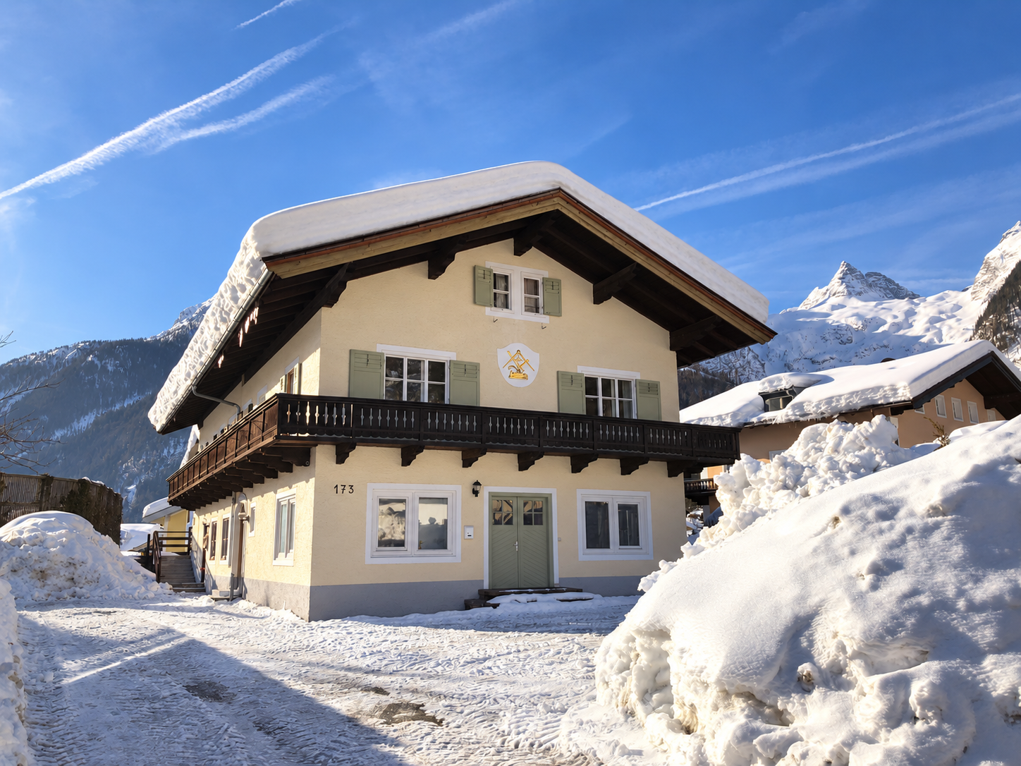Elk Haus in winter, with its timber balcony, snow-covered roof and Alpine mountains